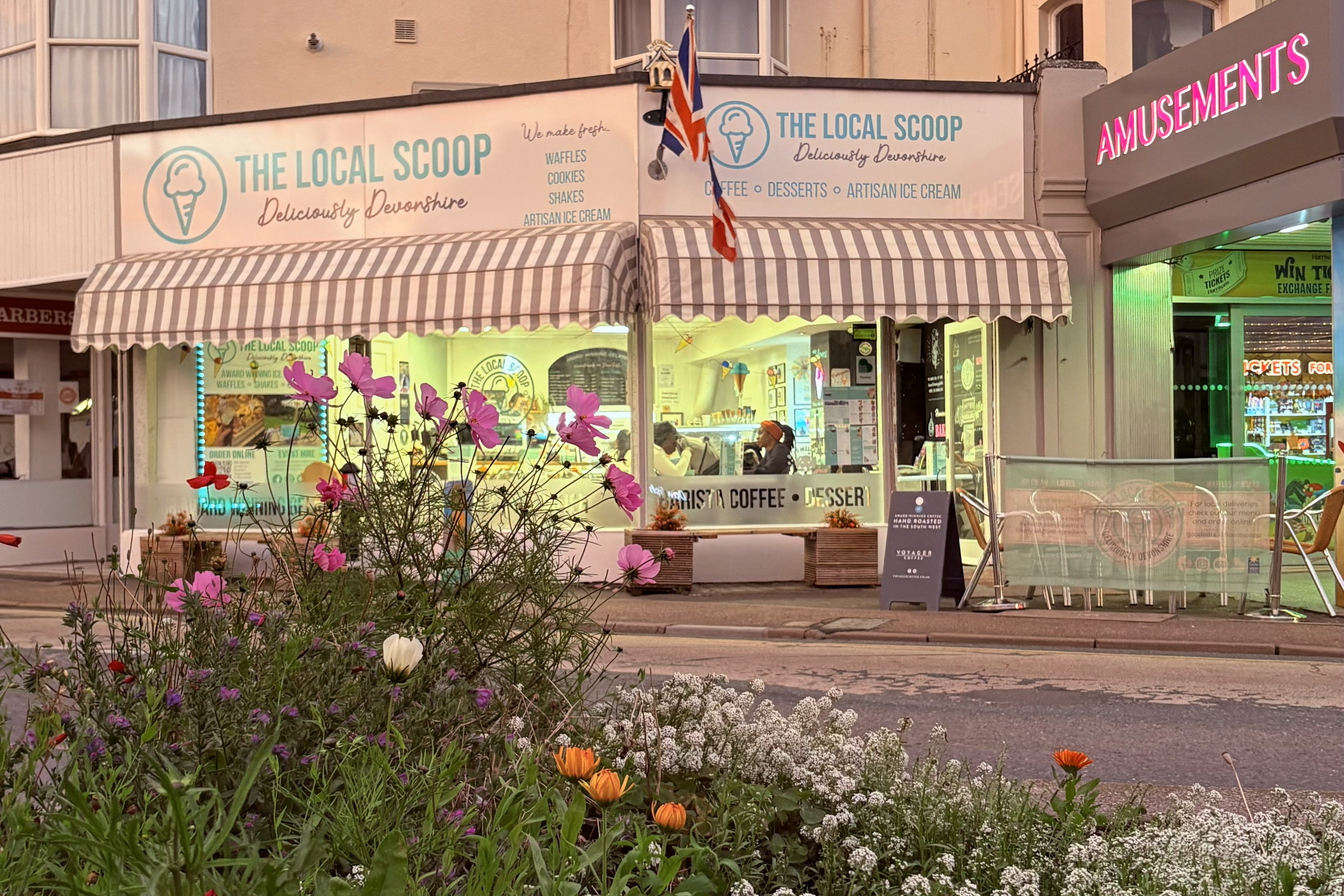  storefront of The Local Scoop ice cream shop with striped awning and outdoor seating area.